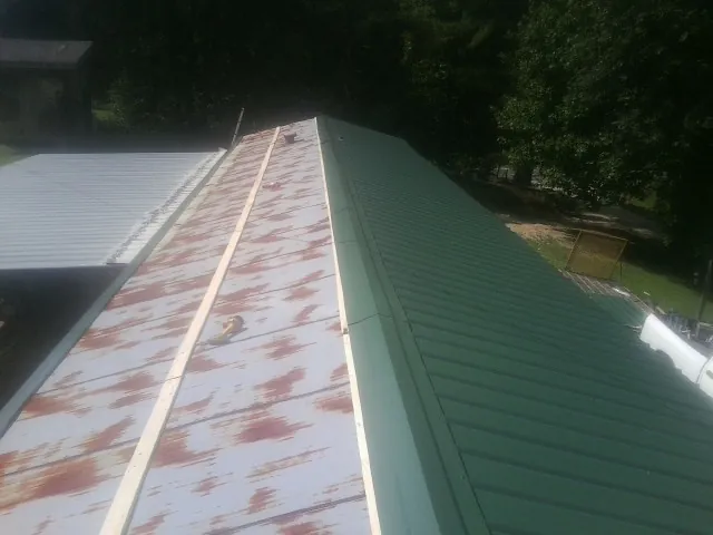 Old rusted panels beside newly installed green metal roofing — Wind Damage Roof Repair by Roofing Brothers in Rush