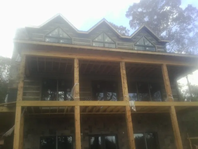 Dormers and porch framing on a large log home under construction — Roof Coating work by our crew in Rush
