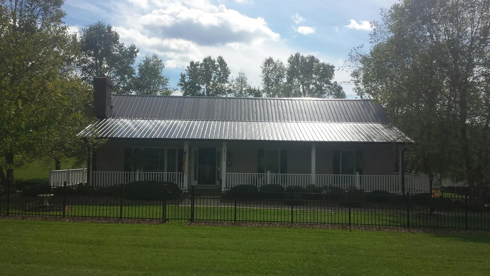 Gray metal roof on a brick ranch with a full width front porch — Gutter Guard Installation work by our crew in Rush