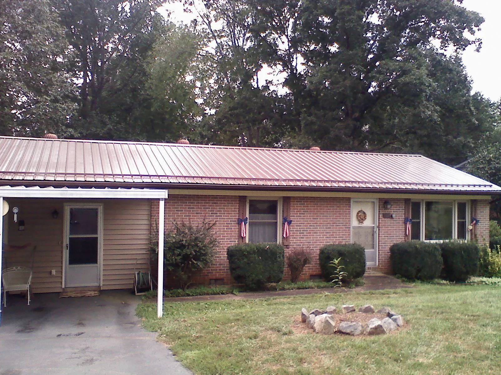 Bronze metal roof and carport on a brick ranch home — Roof Repair work by our crew in Rush